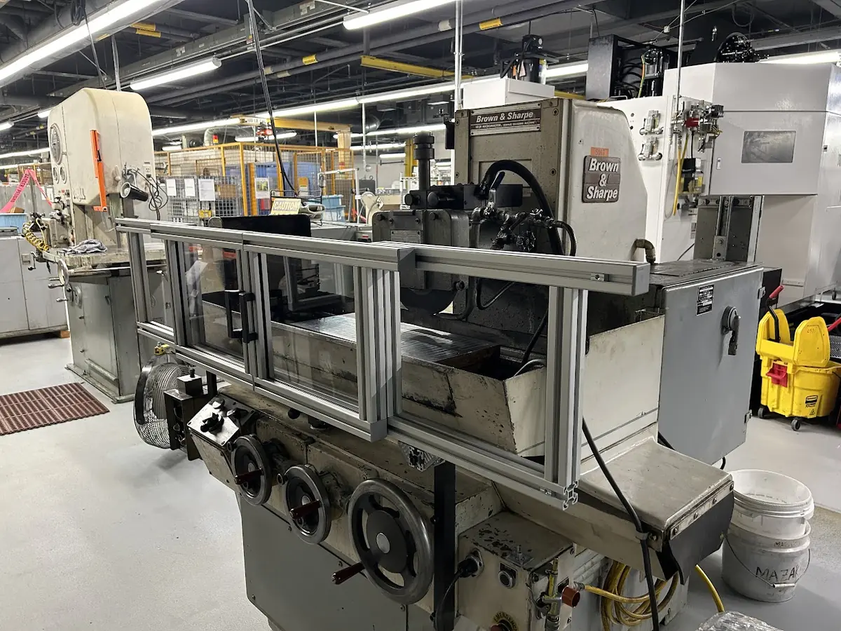Brown & Sharpe surface grinder fitted with a custom aluminum-frame safety guard by American Engineering