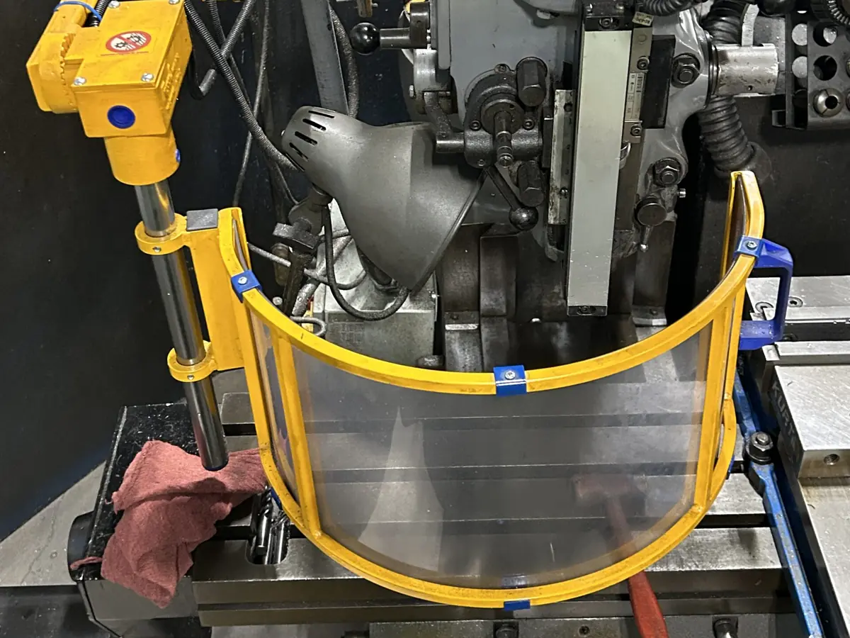 Yellow articulating chip shield guarding the spindle of a Bridgeport milling machine